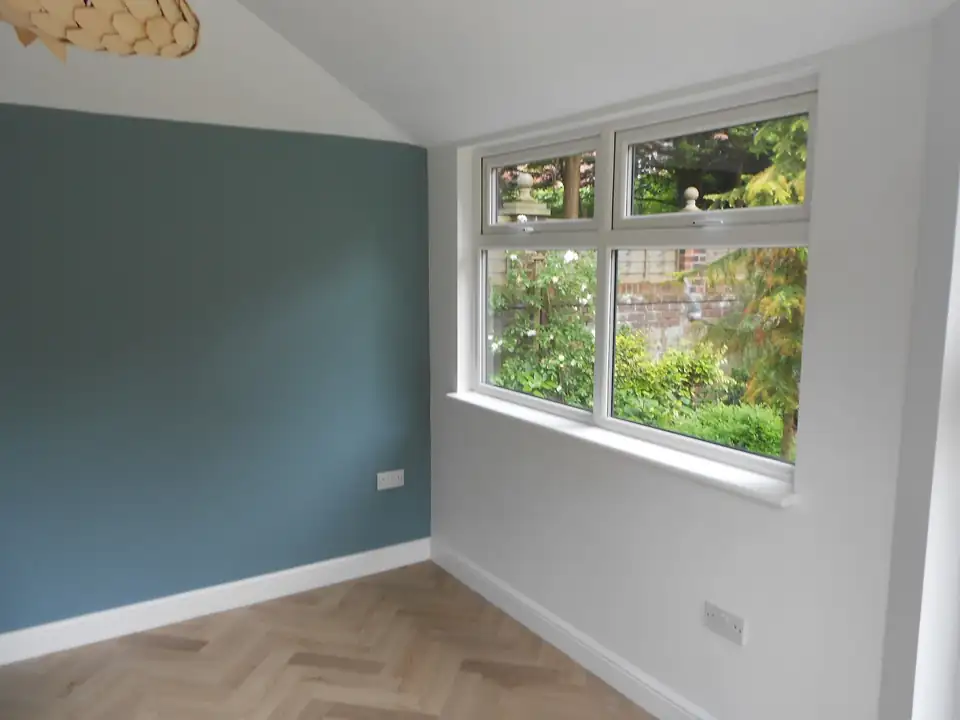 Bedroom in Southport with a blue-grey feature wall, white woodwork and a garden window, decorated by L.S. Painting