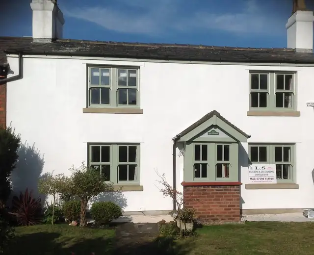 White rendered cottage with sage green window frames and porch, painted by L.S. Painting